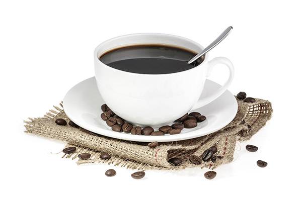 A white cup filled with black coffee on a saucer with coffee beans.