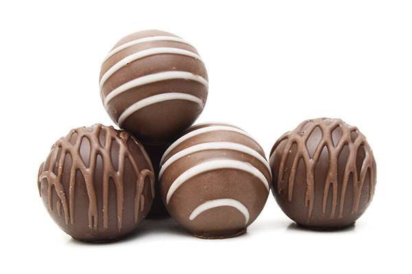 Four round chocolates with white and dark chocolate drizzles.